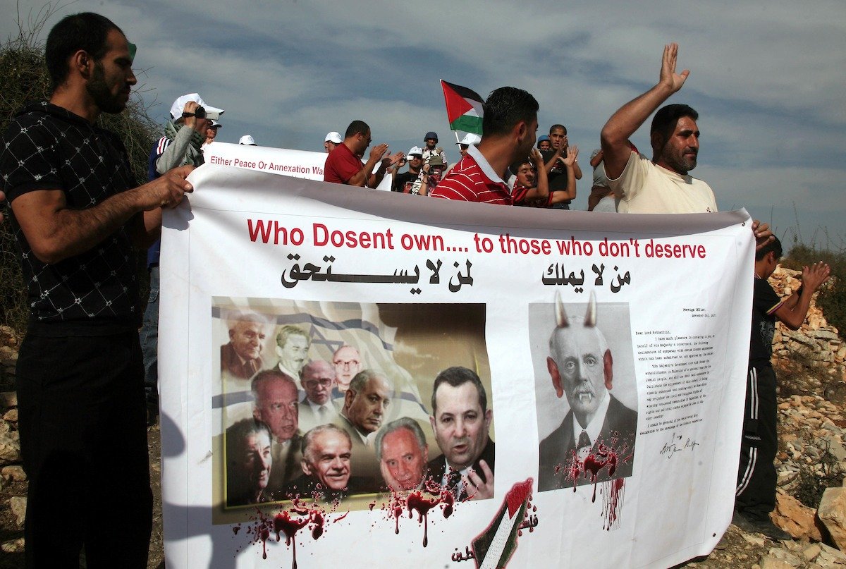 Palestinians hold a banner with a copy of a letter from the British Foreign Secretary Arthur James Balfour to Baron Rothschild (a leader of the British Jewish community) known as the Balfour Declaration of 1917, as Palestinians, Israeli and foreign protesters demonstrate near the Karmi Tsor Jewish settlement not far from the Palestinian village of Beit Omar in the Israeli-occupied West Bank on November 06, 2010. The Balfour Declaration of 1917 is a formal statement of policy by the British government regarding the establishment of a Jewish homeland in Palestine. Photo by Najeh Hashlamoun
