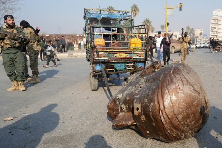 A truck pulls the head of the toppled statue of late Syrian president Hafez al-Assad through the streets of the captured central-west city of Hama on December 6, 2024. - In little over a week, the offensive by rebel forces has seen Syria's second city Aleppo and strategically located Hama fall from President Bashar al-Assad's control for the first time since the civil war began in 2011. (Photo by MUHAMMAD HAJ KADOUR / AFP)