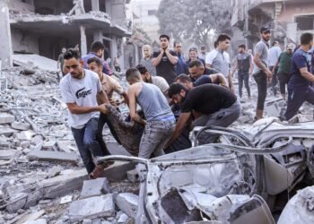 EDITORS NOTE: Graphic content / TOPSHOT - Palestinians evacuate a victim following an Israeli airstrike on Rafah, in the southern Gaza Strip on October 17, 2023, amid the ongoing battles between Israel and the Palestinian group Hamas. Relief convoys which have been waiting for days in Egypt were on October 17, headed towards the Rafah border crossing with the besieged Palestinian enclave of Gaza, aid officials said, as thousands of people, both Israeli and Palestinians have died since October 7, 2023, after Palestinian Hamas militants based in the Gaza Strip, entered southern Israel in a surprise attack leading Israel to declare war on Hamas in Gaza on October 8. (Photo by MOHAMMED ABED / AFP)