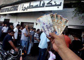 A Palestinian man displays his salary after withdrawing it from an automated teller machine of the Bank of Palestine in Gaza city on July 12, 2012. The Palestinian Authority announced that it will give only 60% of the salary due to the unprecedented crucial financial crisis, Prime Minister Salam Fayyad said. Photo by Ashraf Amra