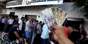A Palestinian man displays his salary after withdrawing it from an automated teller machine of the Bank of Palestine in Gaza city on July 12, 2012. The Palestinian Authority announced that it will give only 60% of the salary due to the unprecedented crucial financial crisis, Prime Minister Salam Fayyad said. Photo by Ashraf Amra