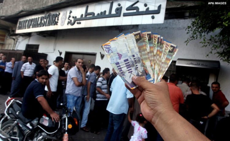 A Palestinian man displays his salary after withdrawing it from an automated teller machine of the Bank of Palestine in Gaza city on July 12, 2012. The Palestinian Authority announced that it will give only 60% of the salary due to the unprecedented crucial financial crisis, Prime Minister Salam Fayyad said. Photo by Ashraf Amra