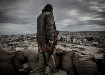 a kurdish fighter walks through the wreckage of a building in the center of the syrian town of kobane