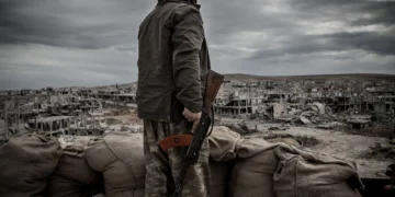 a kurdish fighter walks through the wreckage of a building in the center of the syrian town of kobane