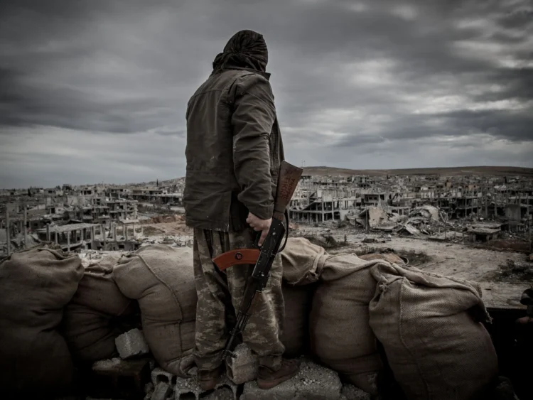 a kurdish fighter walks through the wreckage of a building in the center of the syrian town of kobane