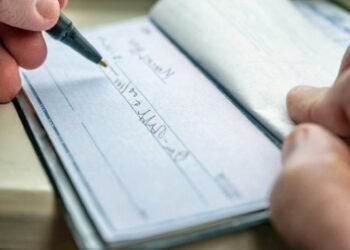 main qui remplie un cheque chequier portefeuille