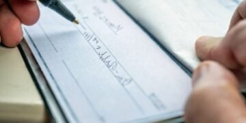 main qui remplie un cheque chequier portefeuille
