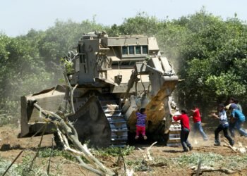 BEIT HANON, GAZA STRIP - MAY 19:  Palestinian boys throw stones at an Israeli tank as it destroys an orange farm May 19, 2003 at Beit Hanoun town in the northern Gaza Strip. Israeli troops continued the seizure of Beit Hanoun in an effort to stop Palestinian militants from firing rockets across the fence into Israel. Palestinian security sources stated that Israeli bulldozers destroyed four more houses and part of a mosque in the northern town of Beit Hanun. The Israelis also razed approximately 49 acres (200 dunams or 20 hectares) of agricultural land in the area which has been the site of heavy military activity since the end of last week. Israeli troops entered the northern Gaza Strip the morning of May 15 in a bid to further dismantle the infrastructure of militant groups and prevent rocket attacks on Israeli targets, many of which are launched from fields around the area.  (Photo by Abid Katib/Getty Images)