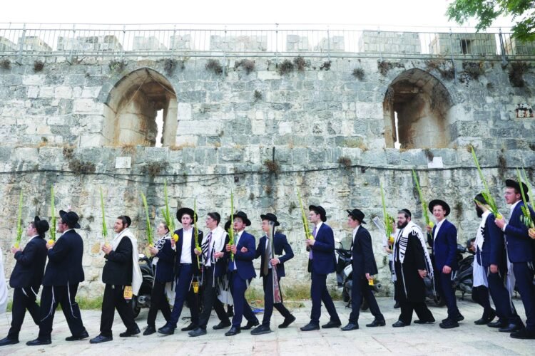 epa10893321 Orthodox Jews pray and hold the four species outside the Lions' Gate, the entrance to the Temple Mount complex and Al Aqsa Mosque, during the celebration of Sukkot, the Feast of the Tabernacles, in the old city of Jerusalem, 01 October 2023. The Sukkot feast, which begins on 29 September at sunset and ends on 06 October, commemorates the exodus of Jews from Egypt some thousands of years ago.  EPA/ABIR SULTAN