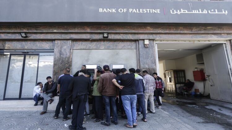 Palestinian employees queue outside a cash machine outside the Bank of Palestine as they wait to withdraw their salaries, in Gaza City on April 9, 2018. / AFP PHOTO / MAHMUD HAMS        (Photo credit should read MAHMUD HAMS/AFP/Getty Images)